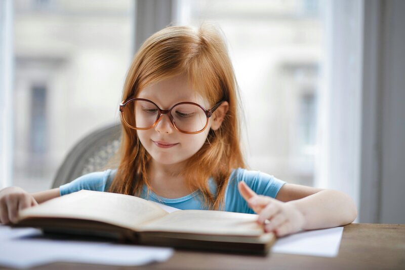 Young girl reading a book at her home