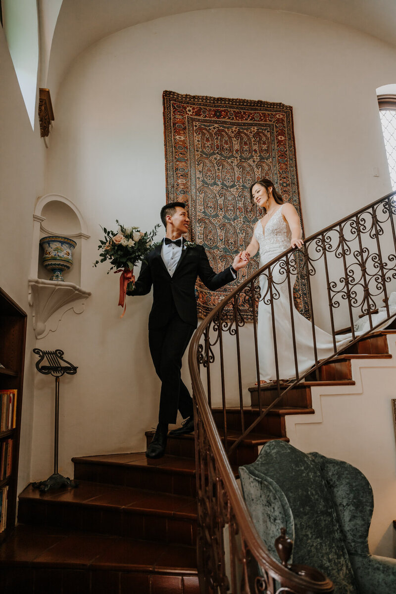 photo of bride and groom walking down curving stairs taken by High-end wedding photography La jolla