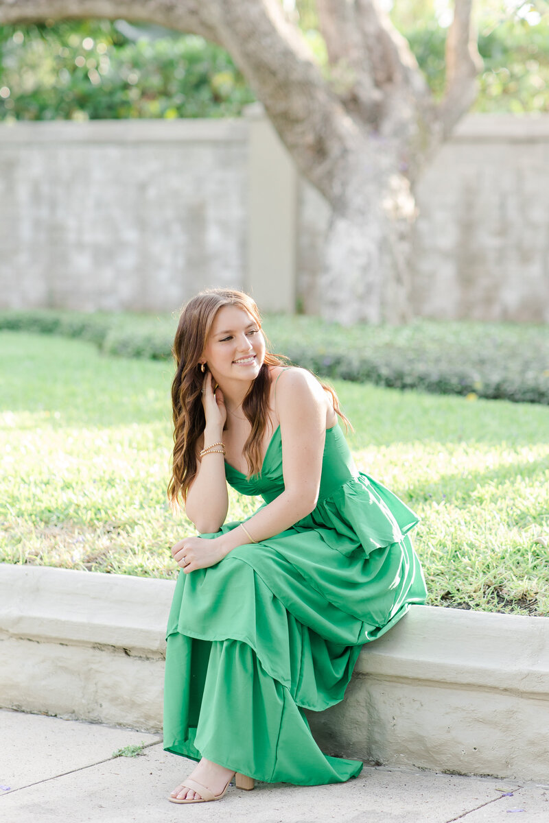 girl sitting on a sidewalk in a green dress