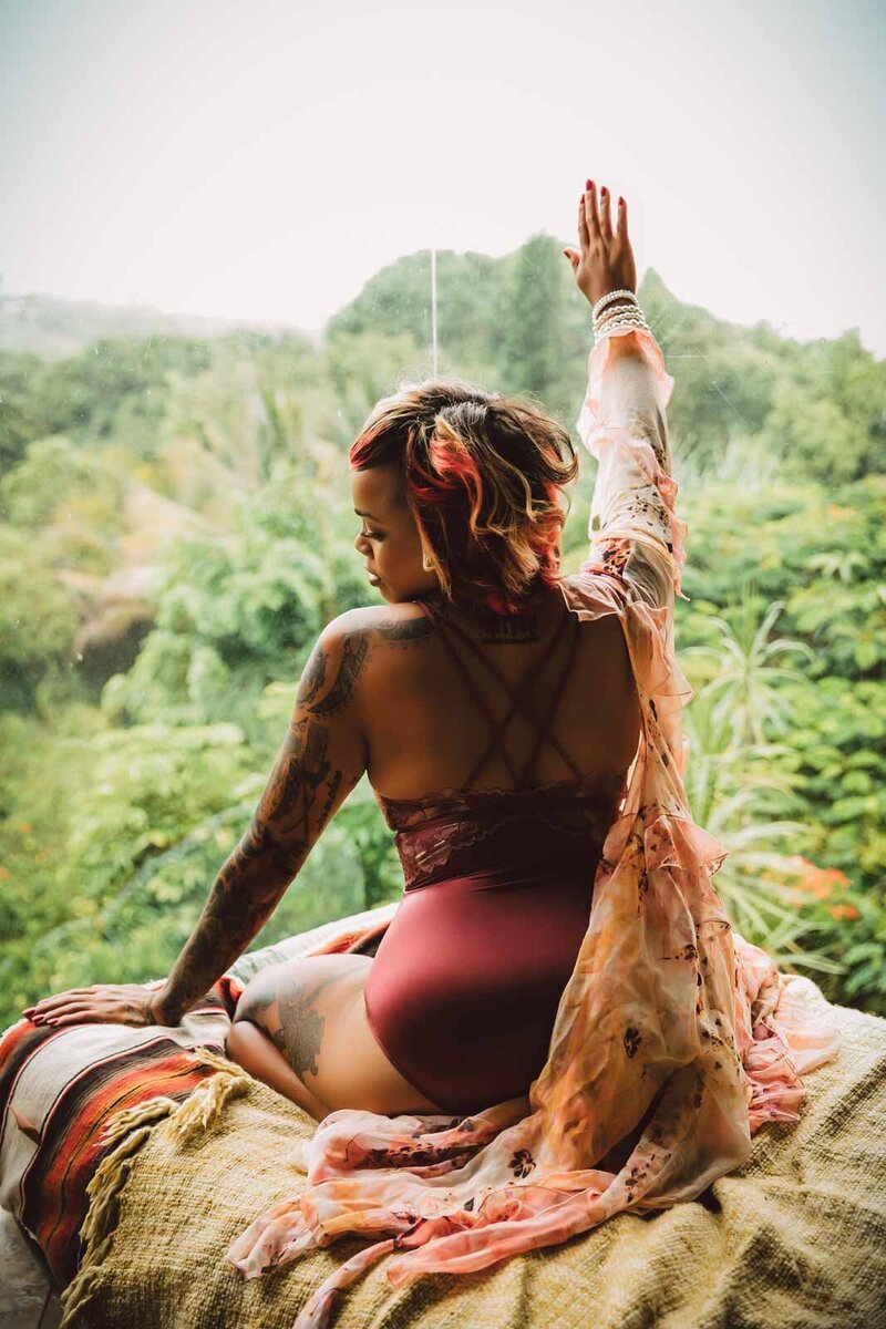 Curvy woman wearing lingerie  in bed looking out window at tropical forest in Hawaii