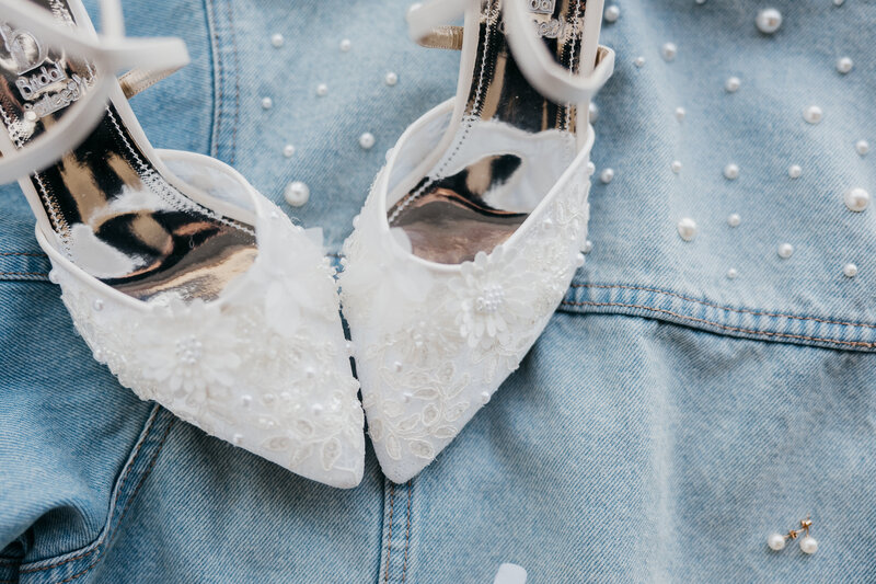 Details of the custom hanger holding the brides dress hanging on the arbor with greenery and light green draping