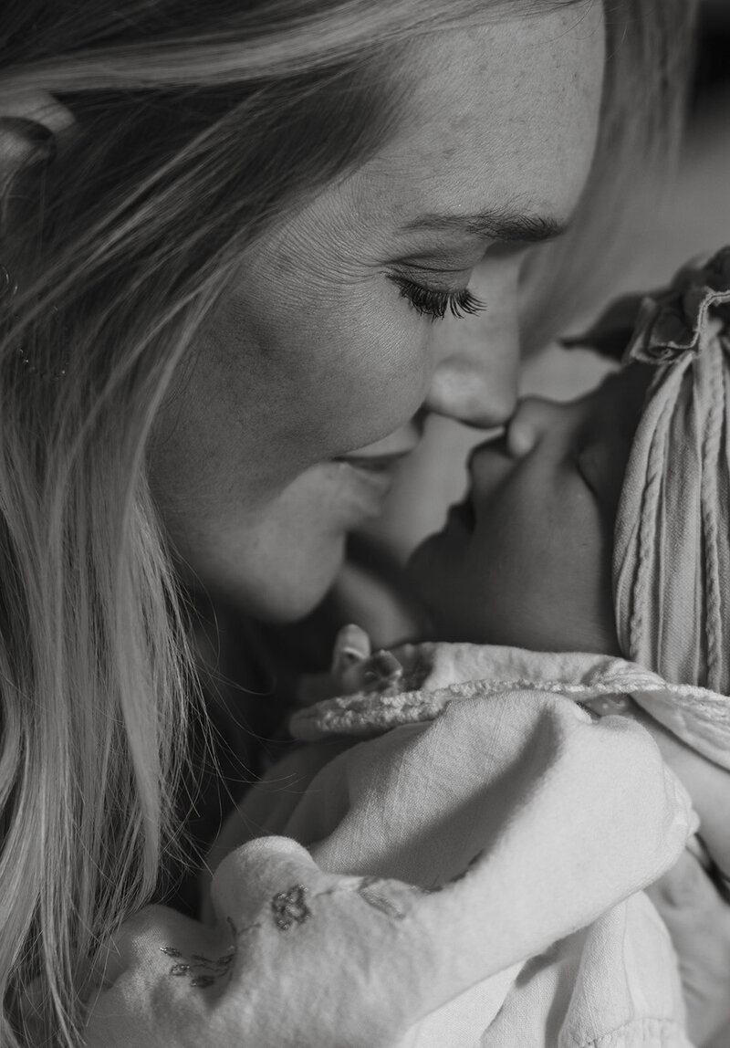 mom and her newborn baby snuggling on the window sill