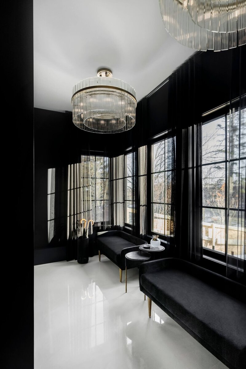 A grand foyer with epoxy flooring, custom black velvet benches and oversized chandeliers. 