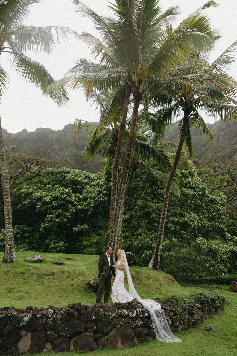 Bride and groom popping champagne on a cliffside at sunset in Maui