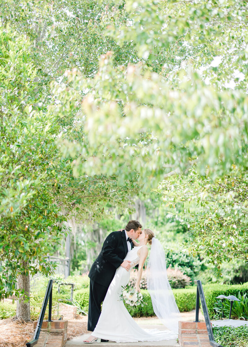 alabama bride smiling into camera while holding white flowers to her face