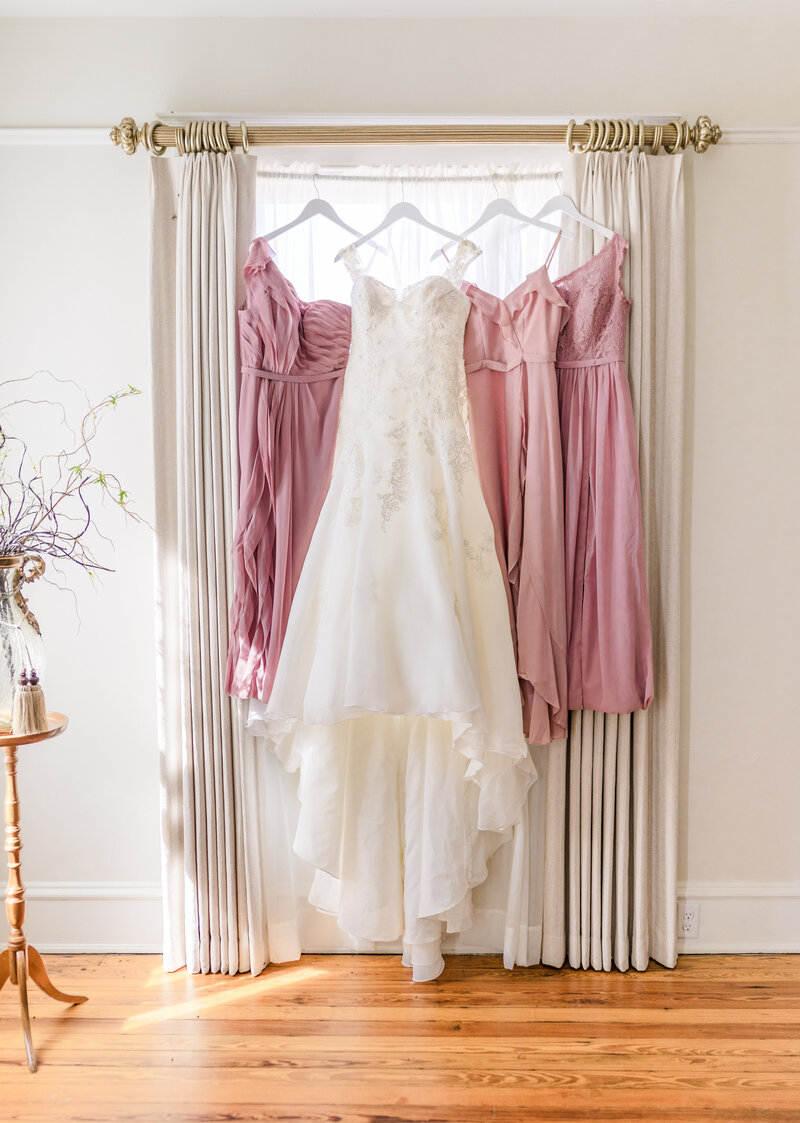Bridal gown and bridesmaids dresses hanging in window