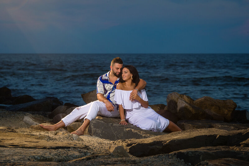 Couple sitting on rocks at New Jersey Shore engagement session