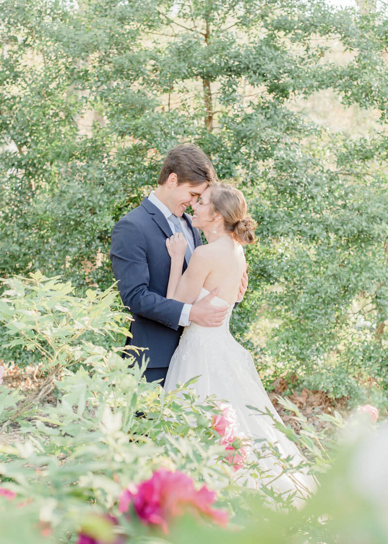 bride and groom facing each other in garden.