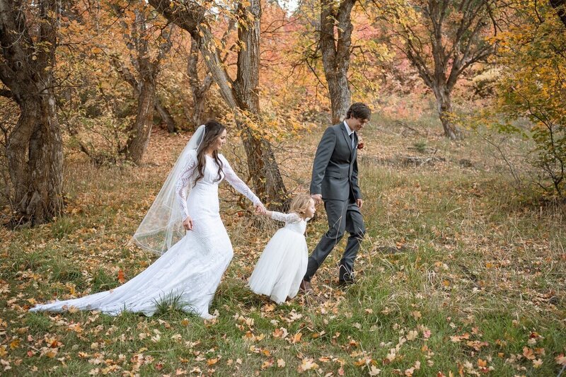 Couple walking hand and hand with their daughter at their elopement in the Utah Mountains. 
