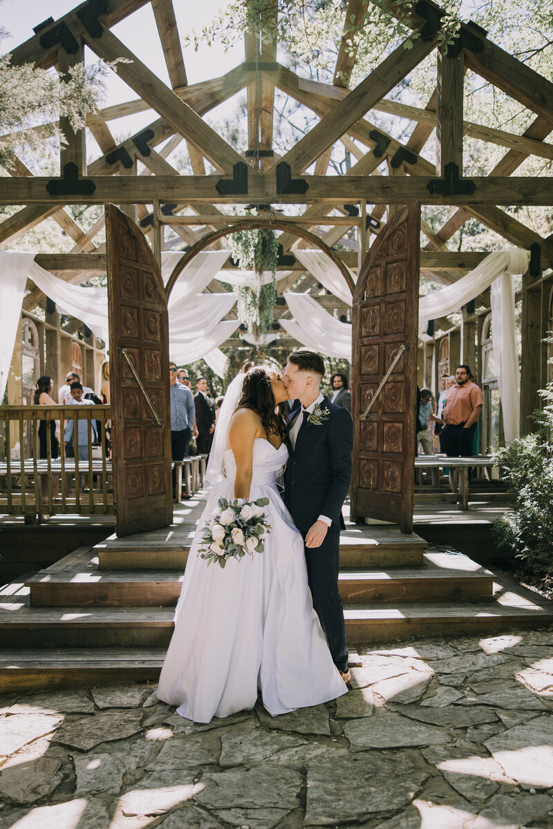 Bride and groom sneak a kiss after their wedding at Bela Sera Gardens in Loxley, Alabama.