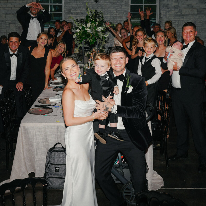 sharing a joyful moment with bride, groom and their son together with their guests at Grbic Events, a wedding venue in St. Louis.