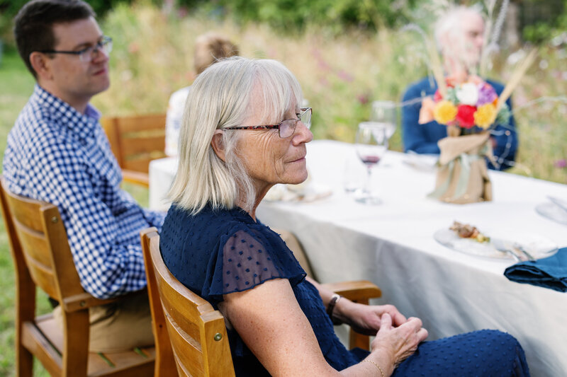 bay area photographers photographs wedding guest outfits in dark blue examples with guests sitting around a table in wood chairs for a california wedding in the outdoors