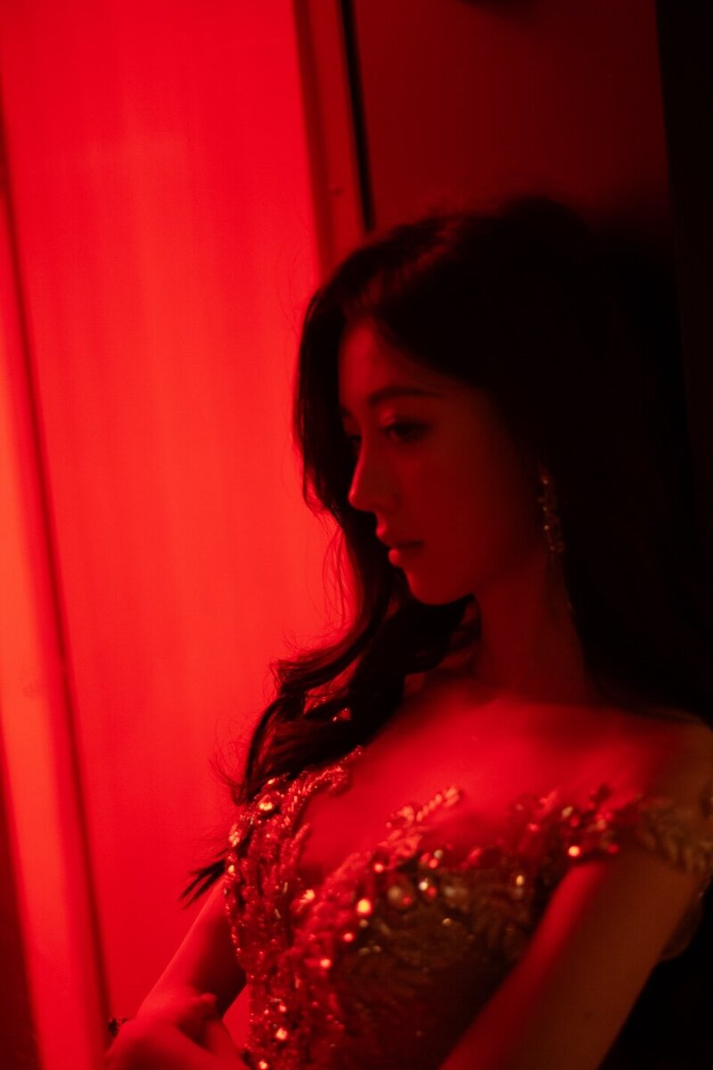 A woman in a red lit room wearing a stunning couture dress.
