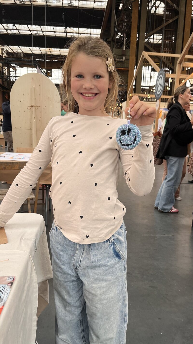 Kind trots met resultaat van een punch needle workshop tijdens een creatieve beurs workshop