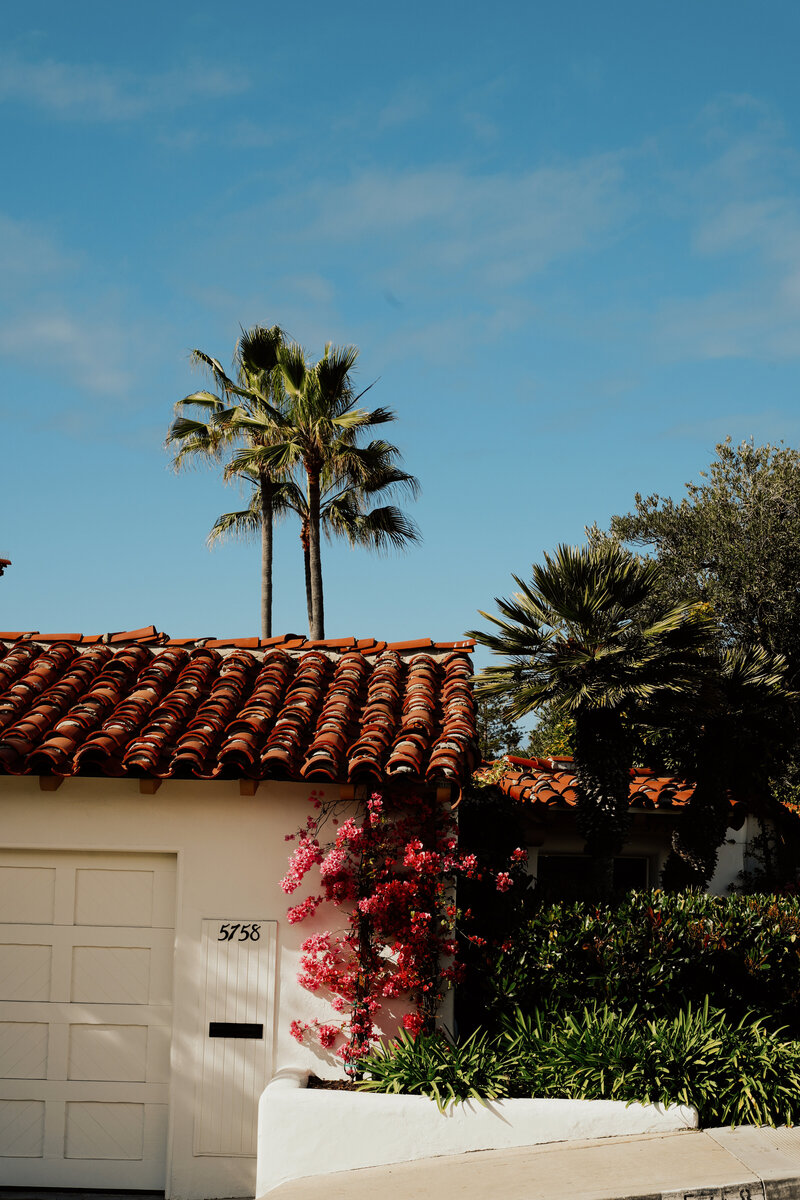 Spanish-style San Diego home exterior with palm trees and vibrant landscaping, showcasing local property style for home sellers — Mary Pernicano Real Estate.