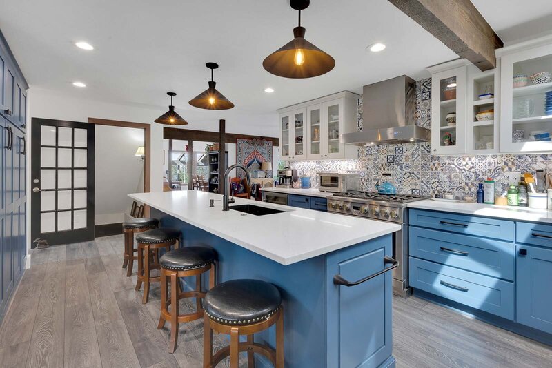 A blue kitchen with dark gray accents and intricate back splash tile.