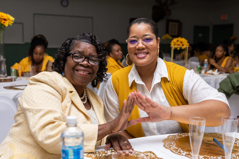 Two women holding hands to form a pyramid
