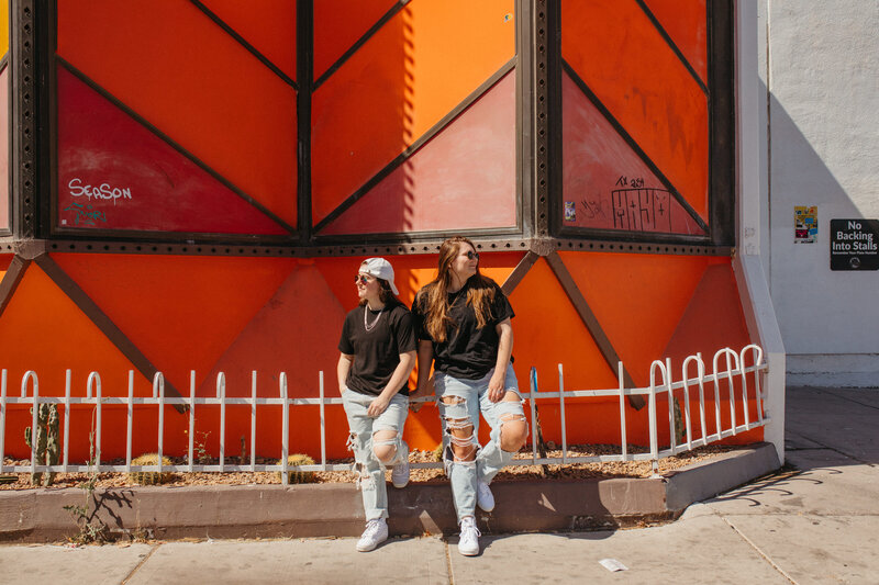 Two people relaxing in front of a red building