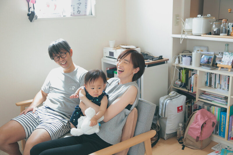 元気な赤ちゃんを見ながらパパとママが大笑いしている明るい写真