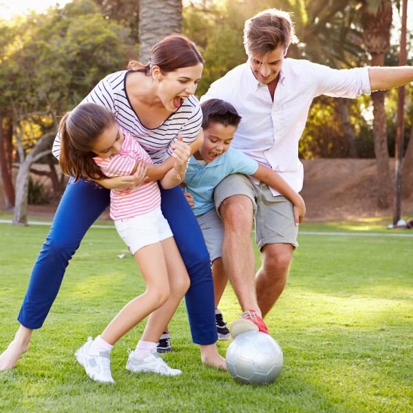 Family enjoying the weekend playing soccer in the park.