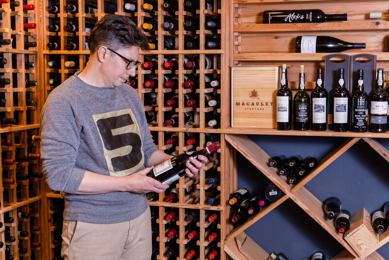 Man in his cellar looking at a bottle of wine during personal branding photo session with laure photography