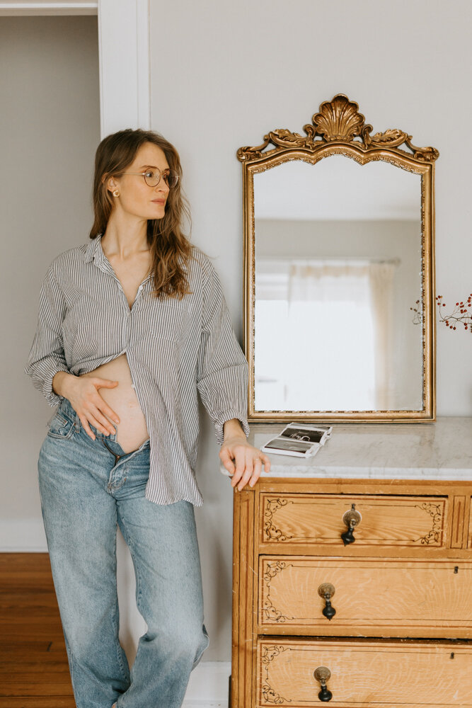 An Indianapolis lifestyle maternity photographer captures an expecting mom in her baby's nursery with a hand on her belly. 