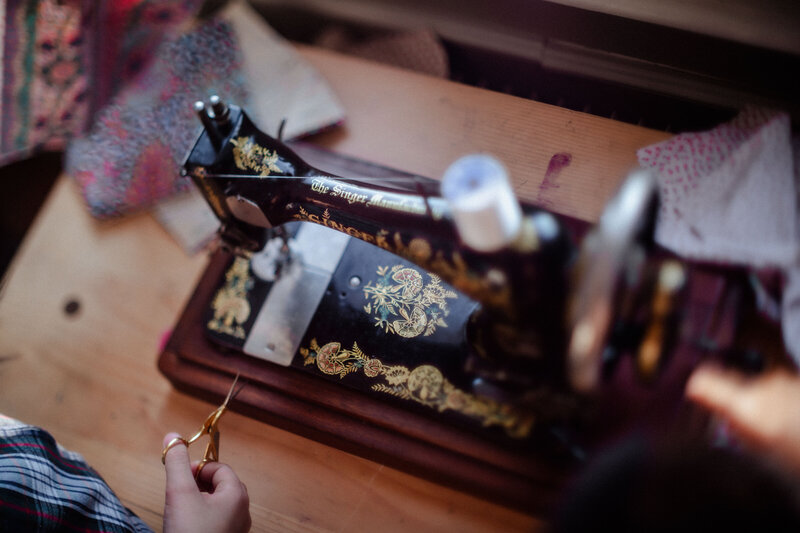 Picture of the hand of  a little girl using a vntage sewing machine and a small scisors