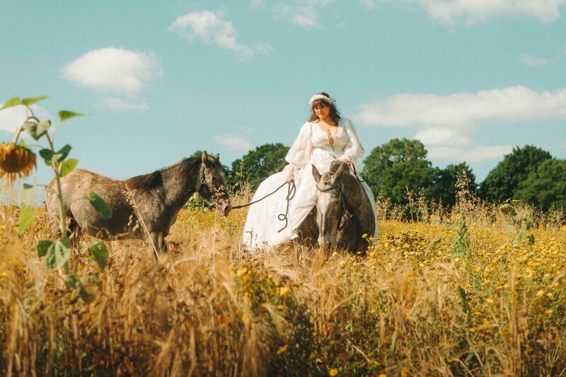 A bride captured prior to her wedding ceremony riding her horses through the scenic Cotswolds countryside