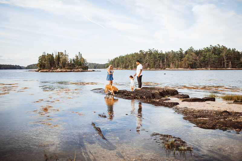 A family on a private maine island with their children and dog sharing a candid moment.