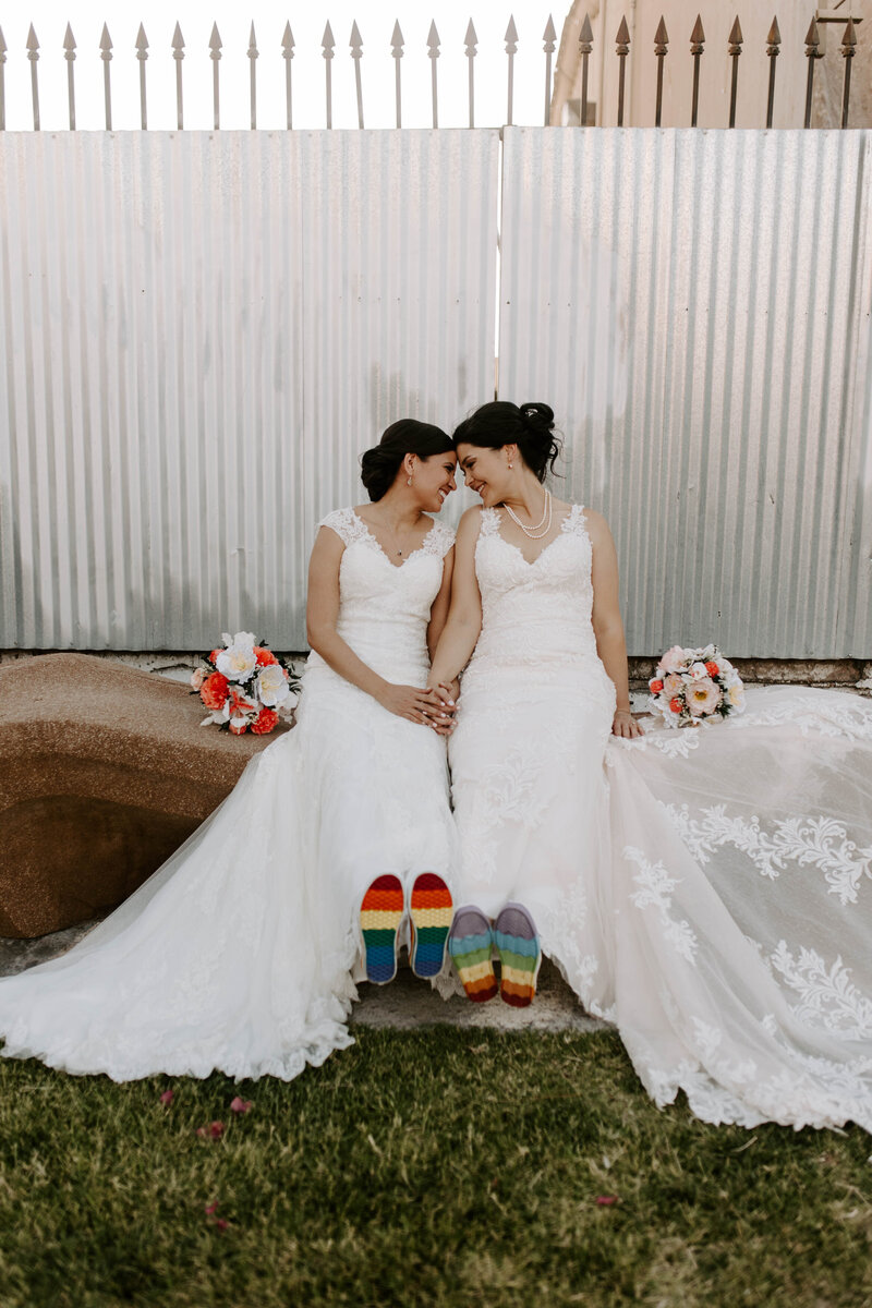 A couple sits face to face smiling with colored converse.