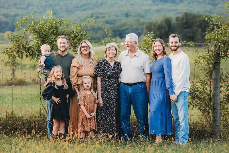 family of four sitting on a log. two little girls sitting on their parents lap in harrisburg family photo taken by kate mccord 