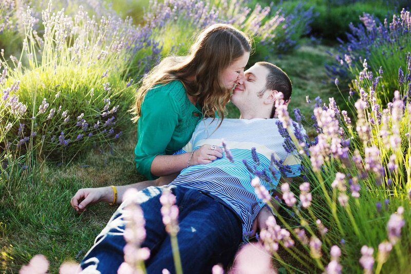 a man and woman touch noses while laying in the middle of a lavender farm