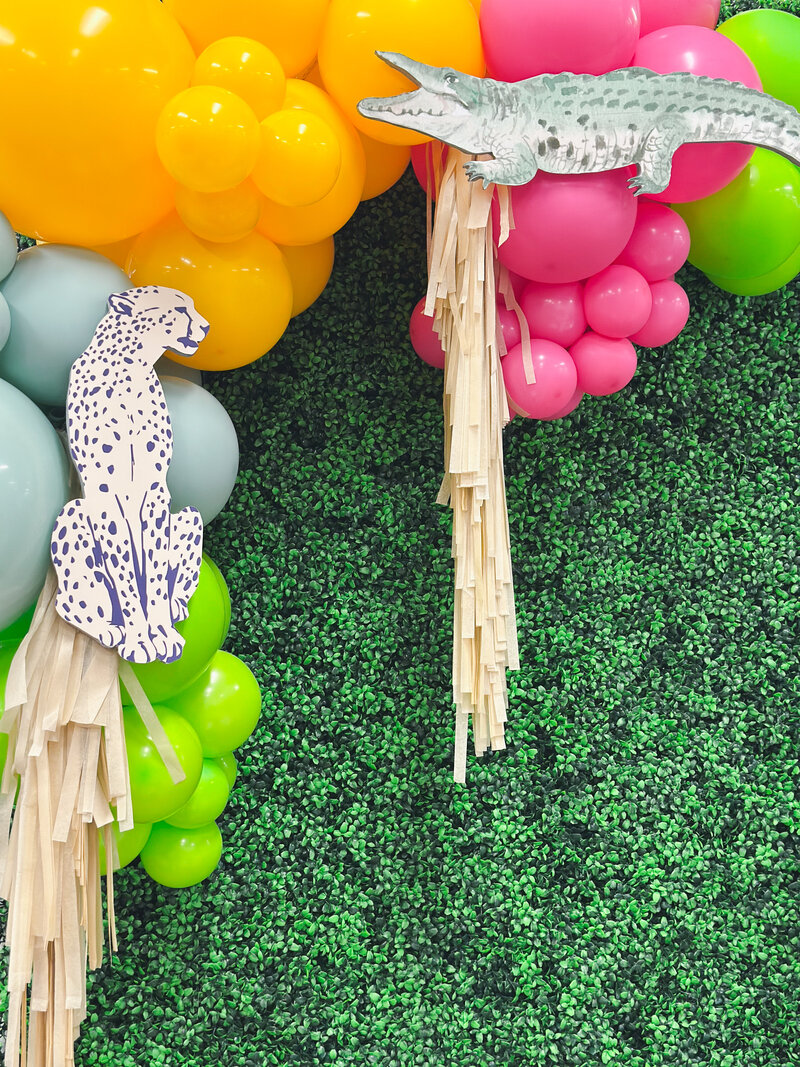 Balloon garland with yellow, pink, green balloons and cheetah and alligator decorations.