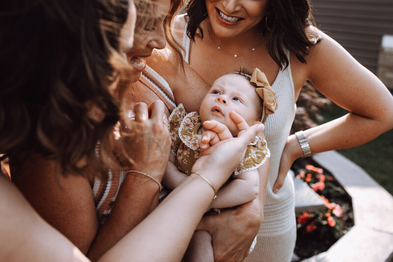 A group of women in a family gush over the adorable baby.