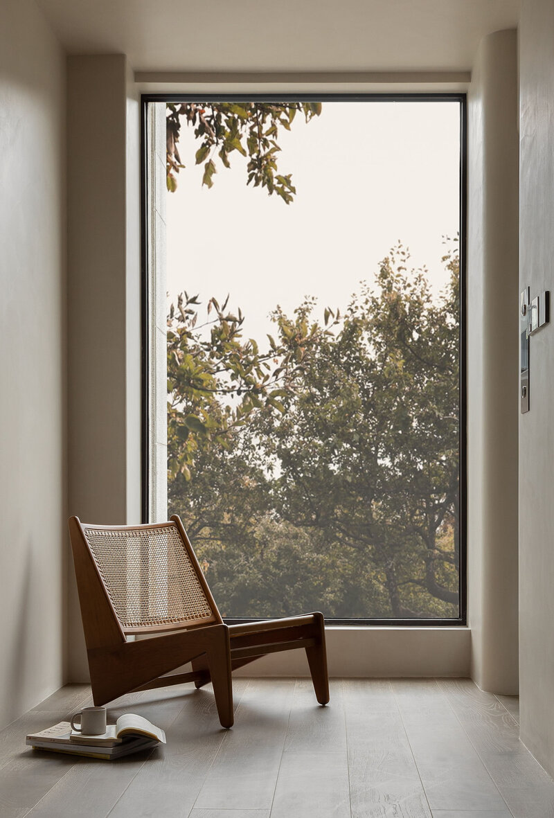 Scnadinavisch ontwerp van een stoel  in een lichte ruimte bij een groot raam met zwart kozijn