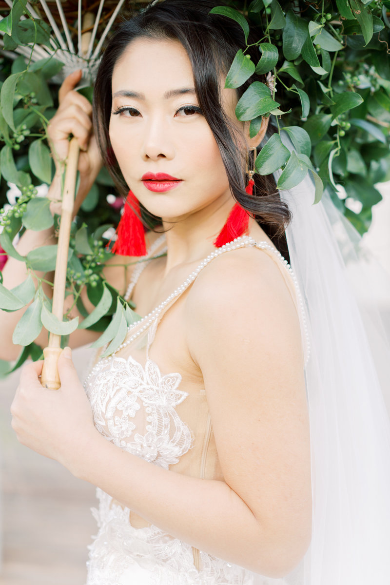 A stunning fine art bridal portrait with lush greenery, bold red lips, and refined elegance—perfect for luxury weddings.