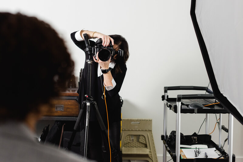 a photo of Ottawa Headshot Photographer JEMMAN Photography COMMERCIAL looking through the lens as she photographs a client in the studio