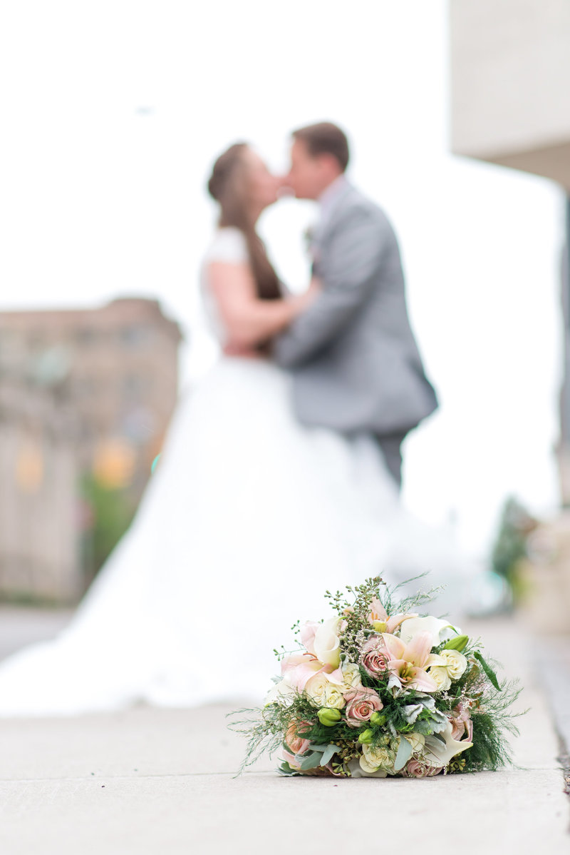 Picture of bouquet with bride and groom blurred in the background
