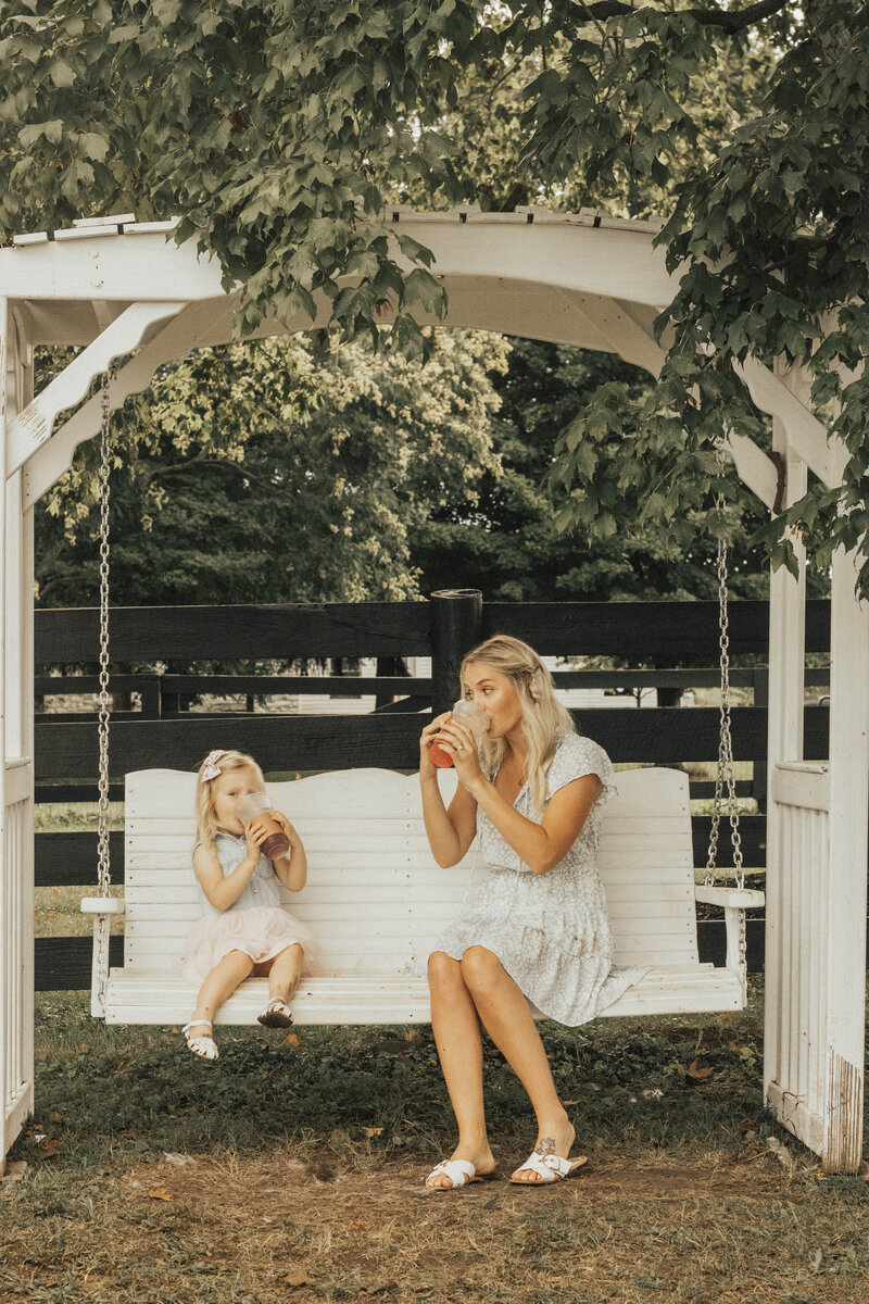 bride and flower girl sitting on porch swing