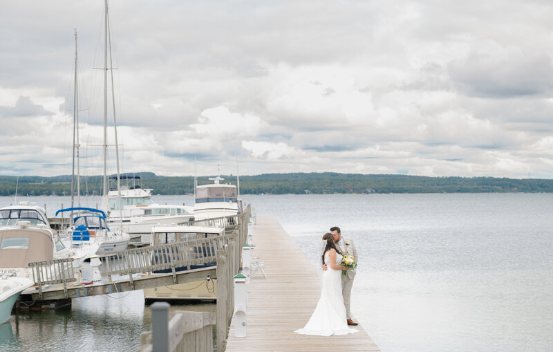 A bride and groom stand on a dock with sailboats at their wedding in Northern Michigan