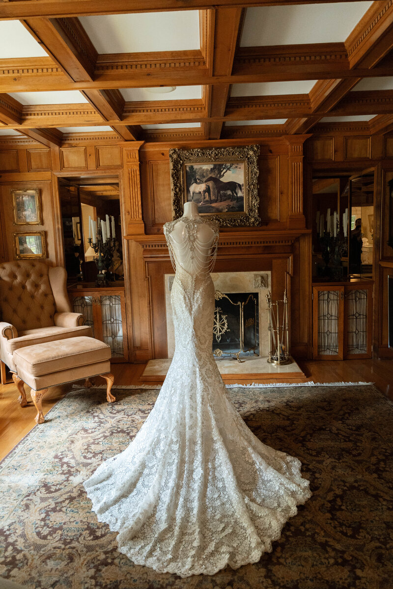 Lace wedding gown displayed in vintage wood-paneled room before ceremony, captured by luxury Arkansas wedding photographer.