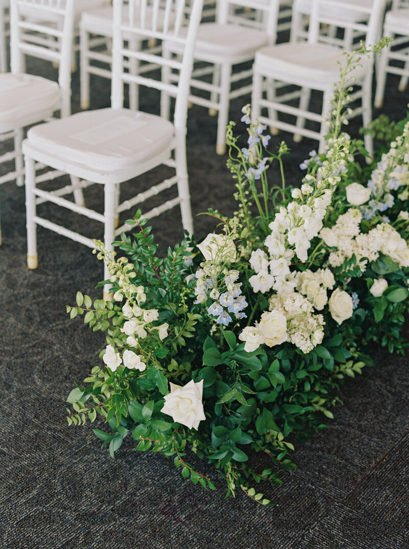 ceremony aisle flanked by greenery and white roses at Discovery World