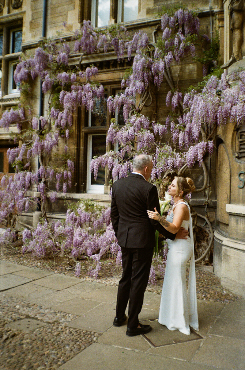 Bride and groom cuddling beside some wisteria at a luxury wedding venue in Kent.