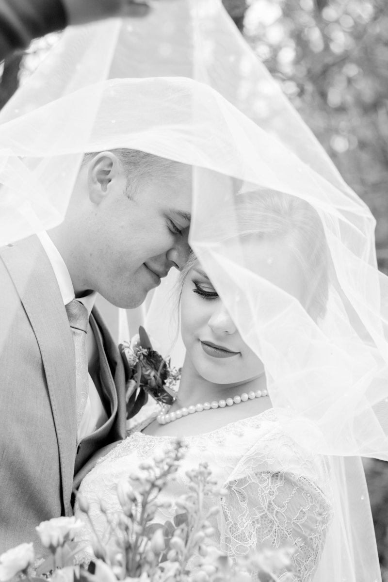 Affordable Washington elopement photographer captures bride looking at groom while holding bridal bouquet during forest wedding