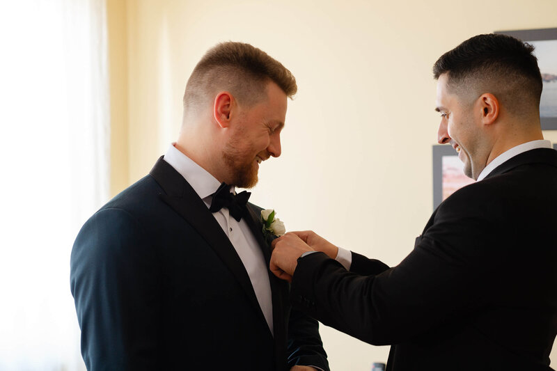 best man adjusting the groom's boutonniere.  Captured by Ottawa wedding photographer JEMMAN Photography
