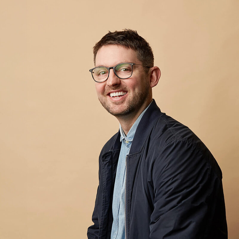 Man in navy top against a beige coloured background.