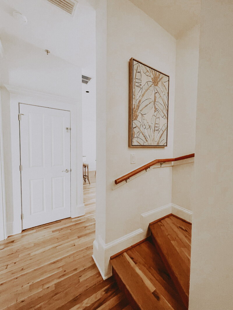 white hallway with wooden floors and abstract painting on the wall