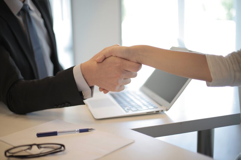 business man sitting at desk shaking hands with another person