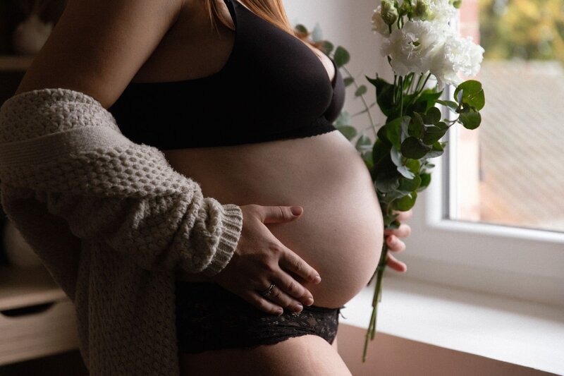 Cliché du ventre rond de la future maman lors d'une séance grossesse cocooning et intimiste à domicile à Colombe en Isère