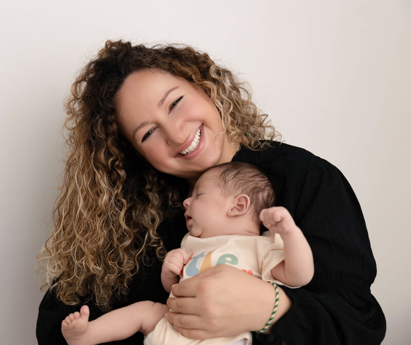 Mom holding newborn baby boy against her for photos at Heather Nicole Photography.